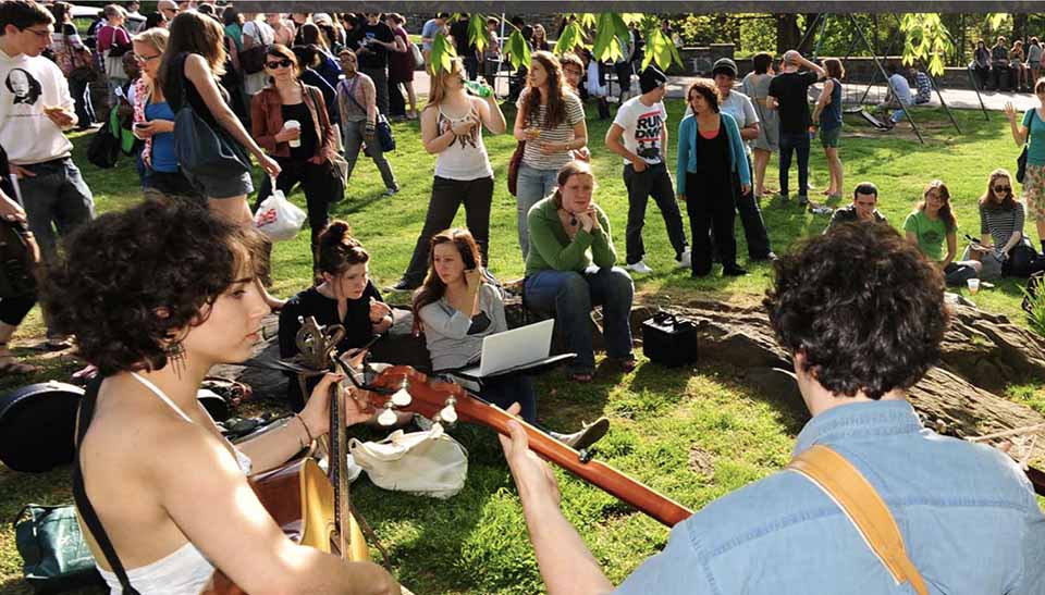 large group of students outdoors with students playing instruments in the foreground