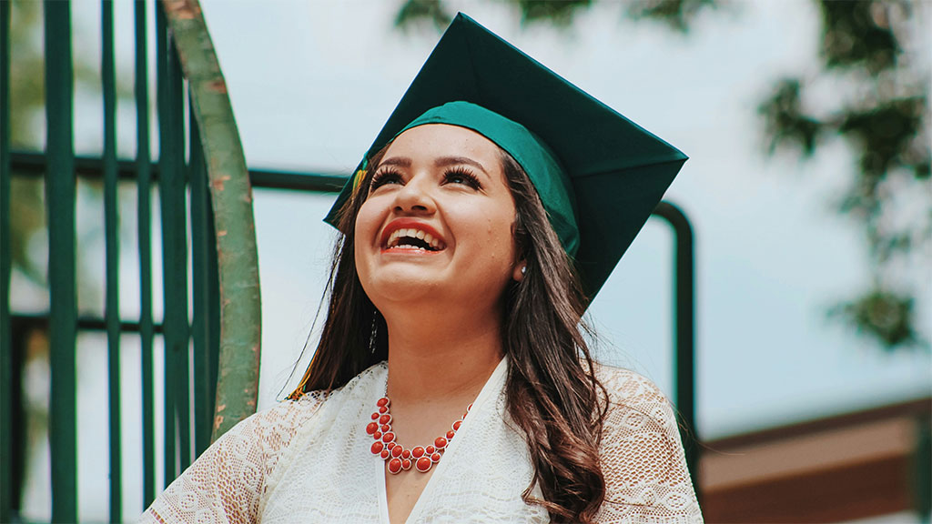 A smiling student raising her hand in class