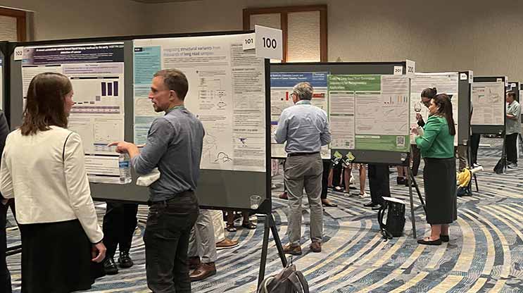 People mingling in between scientific posters in a hotel ballroom.