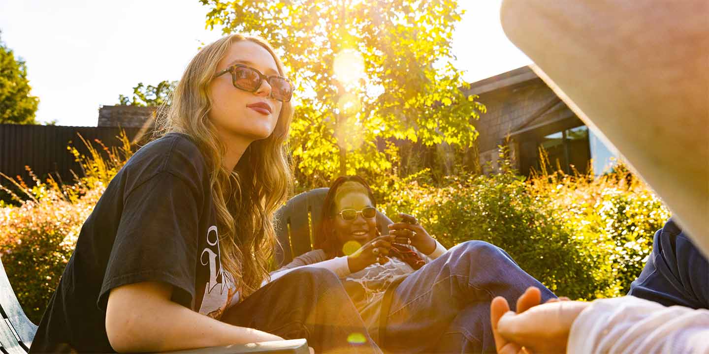 Students sitting outside in conversation with the sunset in the background