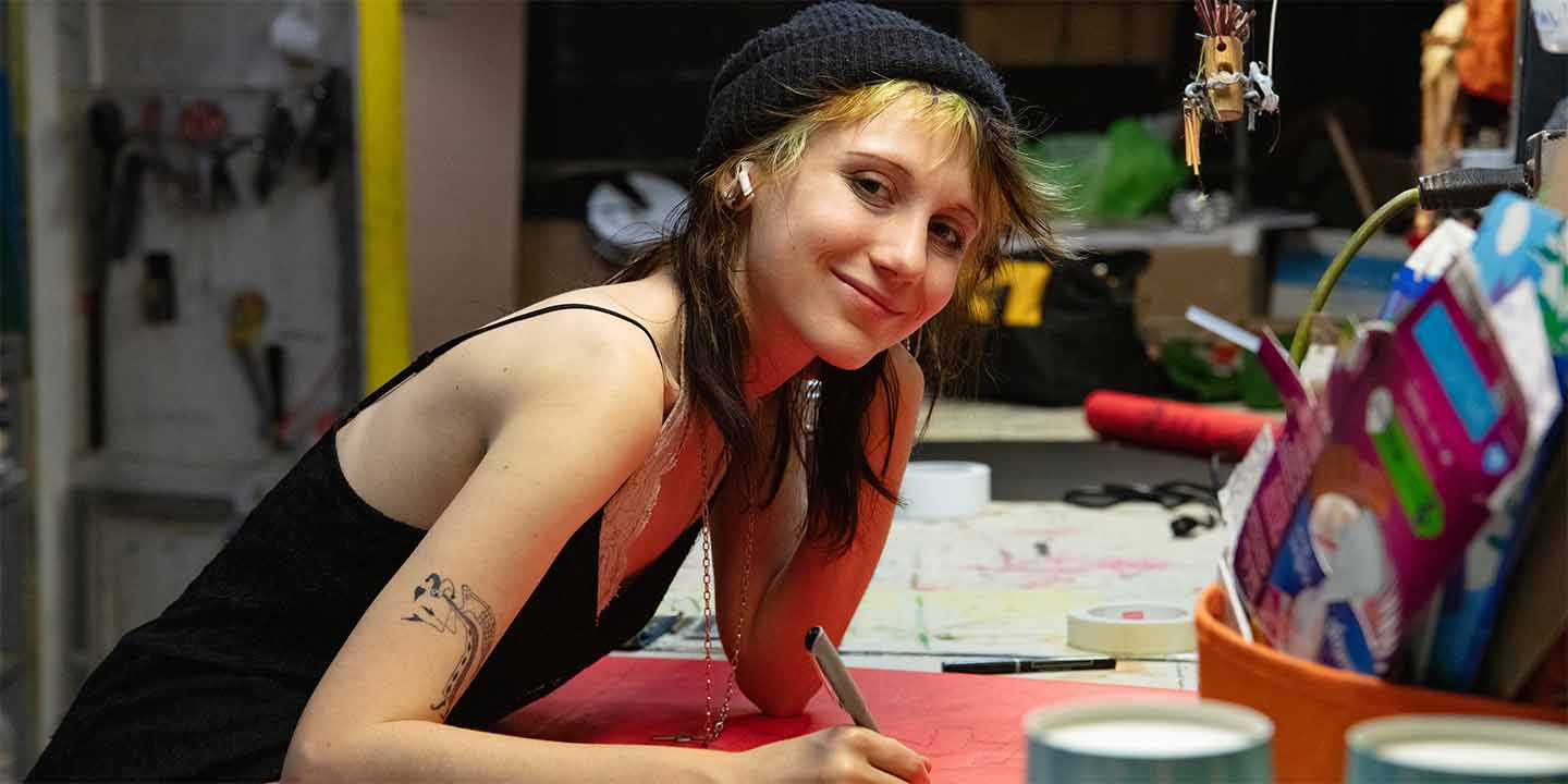 student working in the puppetry studio smiling at the camera