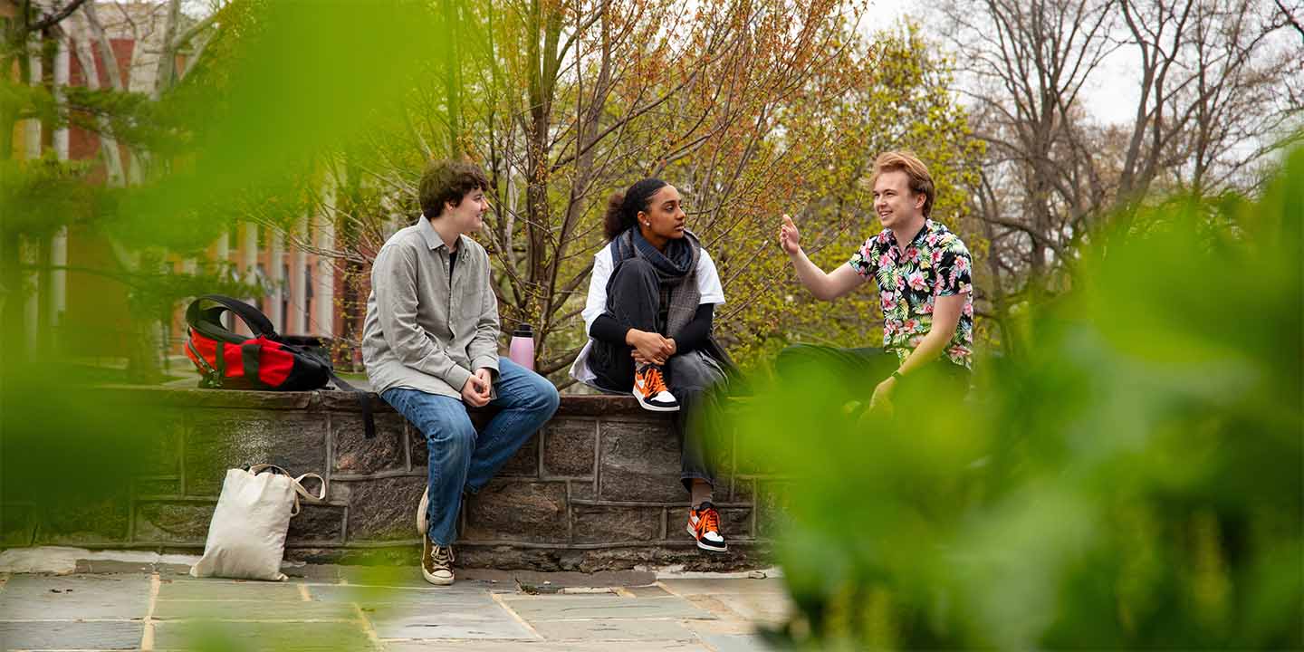 students in conversation sitting on outside on a patio wall