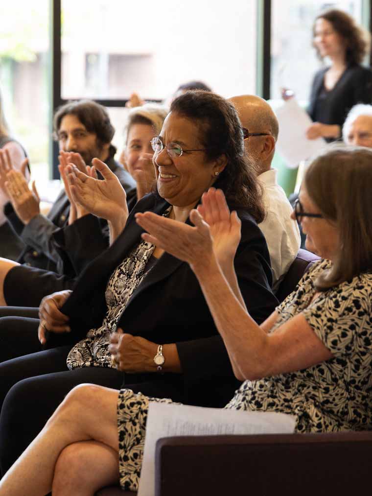 people seated and applauding in a large venue