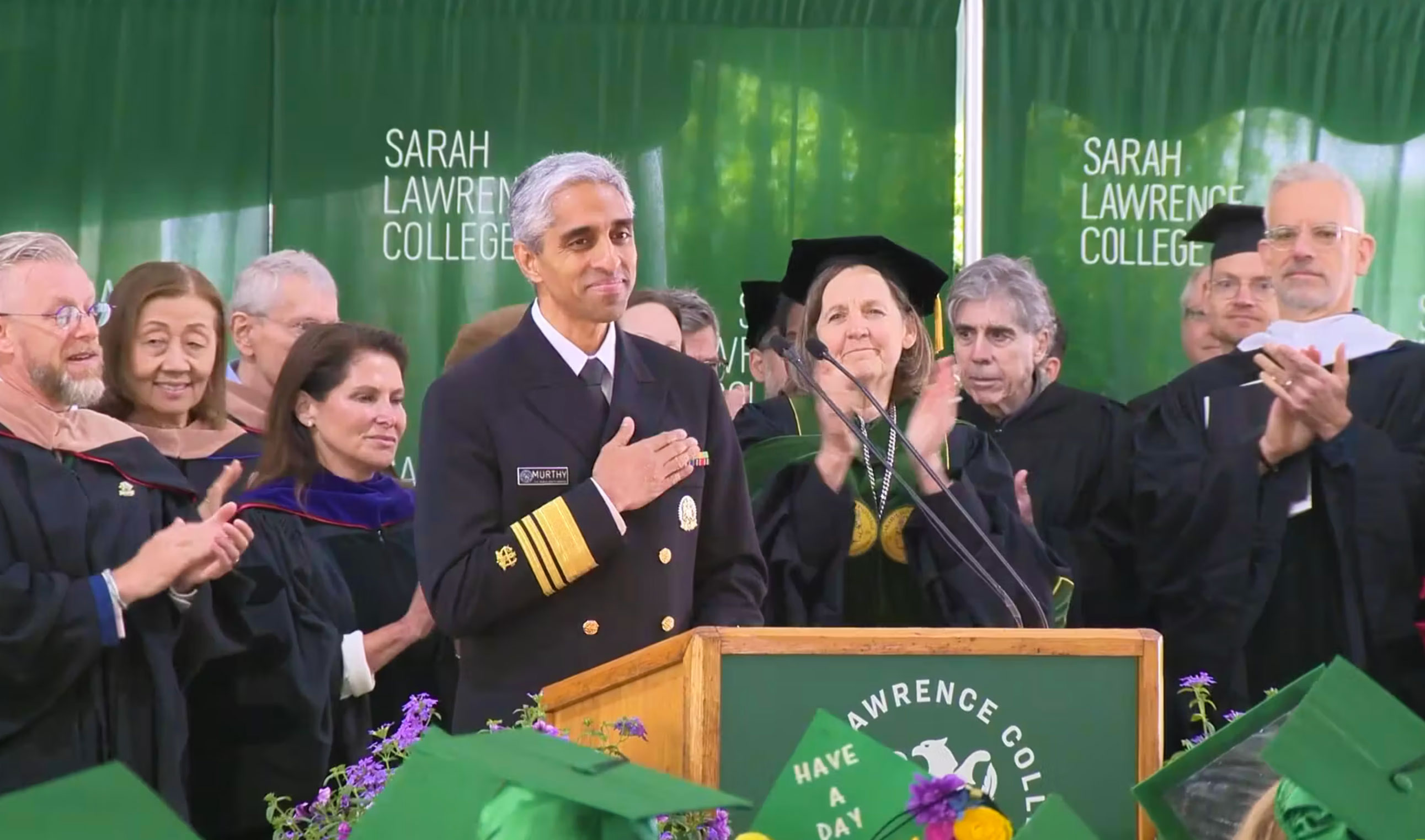 U.S. Surgeon General Vivek Murthy holds hand over heart while receiving a standing ovation
